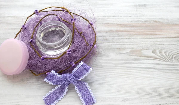 Beyaz ahşap zemin üzerinde krem jel Cilt Bakımı Cilt care.open kavanoz. Mor sisal. Mor yay