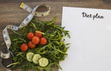 Diyet planı, menü veya program, ölçme bant ve diyet gıda taze roka ve domates koyu ahşap arka plan, kilo kaybı ve detoks kavramı, üstten görünüm