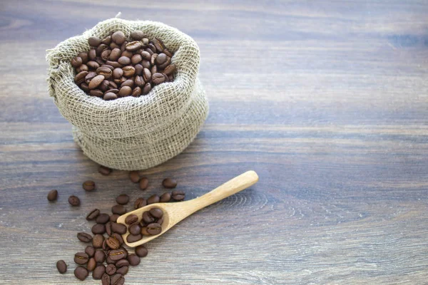 Kavrulmuş kahve çekirdekleri bir ahşap zemin üzerine bir torba dağınık kahve fasulye
