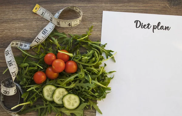 Diyet planı, menü veya program, ölçme bant ve diyet gıda taze roka ve domates koyu ahşap arka plan, kilo kaybı ve detoks kavramı, üstten görünüm