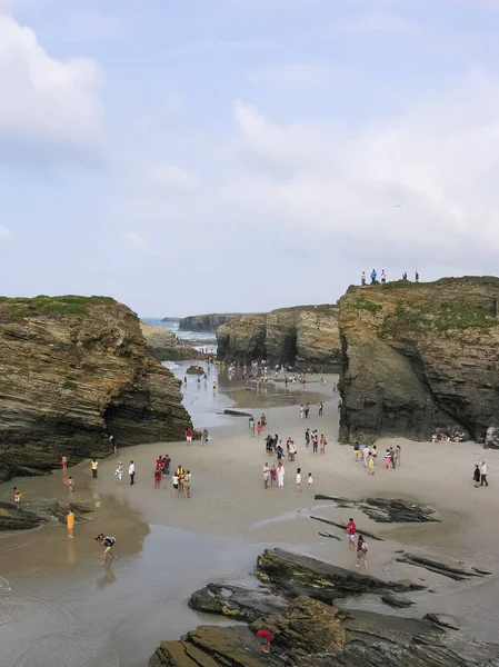 Kuzey İspanya'da kayalıklar arasında bir plaj boyunca yürüyen insanlar