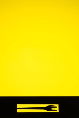 Sarı arka plan üzerinde siyah bir çatal tarafından oluşturulan yüksek kontrast Natürmort görünümü