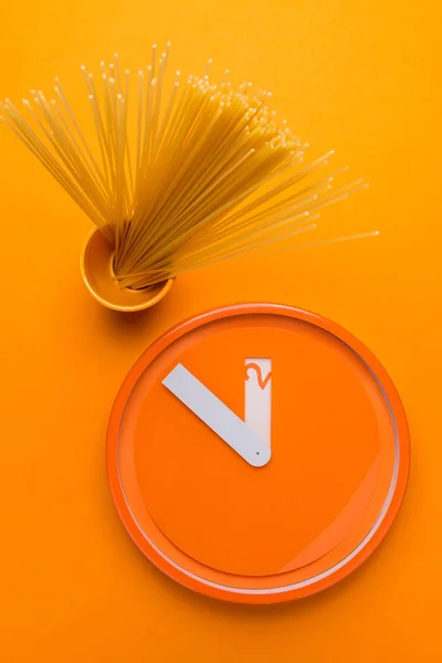 Set of spaghetti next to orange kitchen clock — Stock Photo, Image