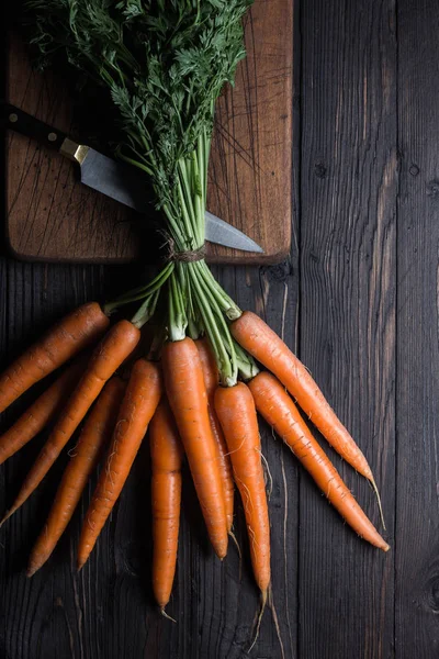 Bıçak ve kesme tahtası üzerinde, ip ile bağlı havuç demeti, havadan atış