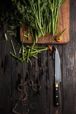 Rustik masada havuç sapları, kesme tahtası ve bıçak