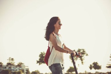 Elektrikli scooter giyen kadın yırtık kot giyiyor