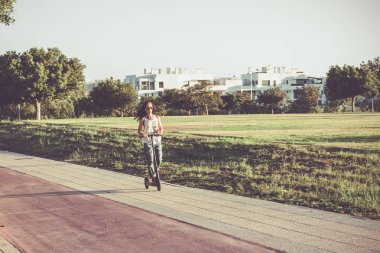 Elektrikli scooter giyen kadın yırtık kot giyiyor