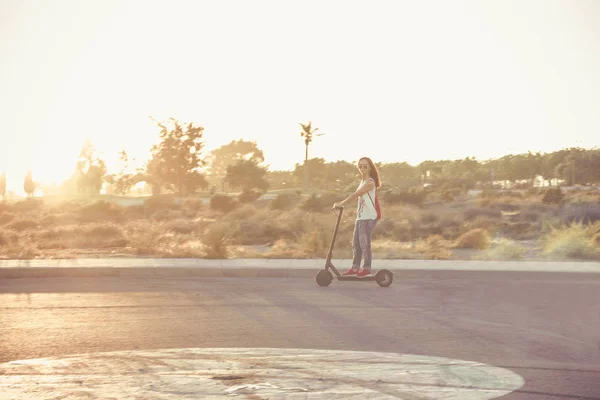 Mujer montada en scooter eléctrico al atardecer — Foto de Stock