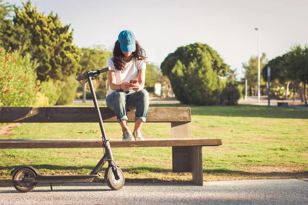 Kadın, elektrikli tekme scooter yanında, parkta cep telefonu yla sohbet