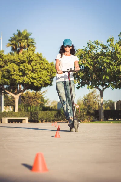 Kadın, kırık kot giymiş, elektrikli tekme scooter sürme