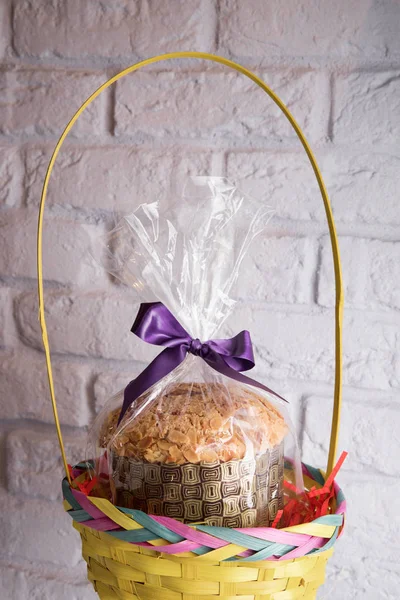 Packed homemade Easter cake with nuts decorated with a slice of orange in a basket on a light background
