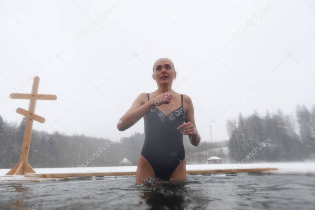 Girl in a swimsuit dipped in the hole in the winter. Orthodox feast of the baptism of the