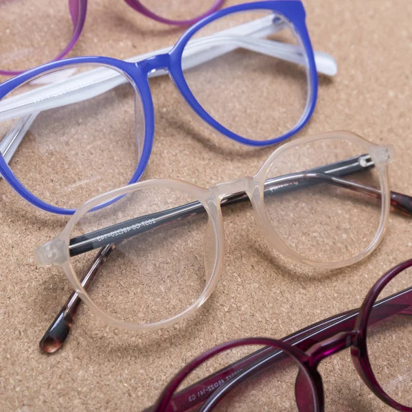 Different eyeglass frames on cork board