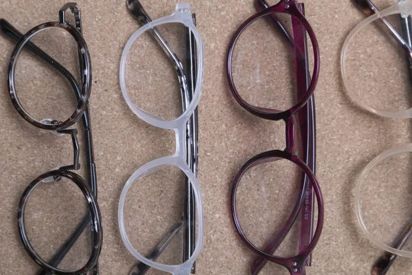 Different eyeglass frames on cork board