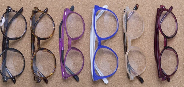 Different eyeglass frames on cork board