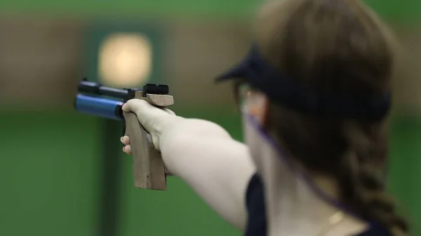 The girl shoots from a professional air gun. Selective focus on hand