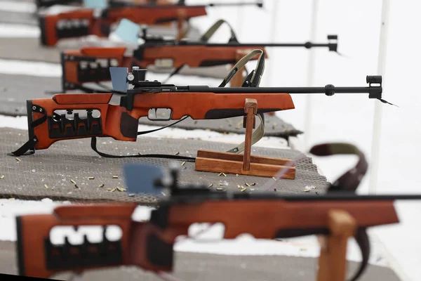 Biathlon rifles are on the mat at the shooting range