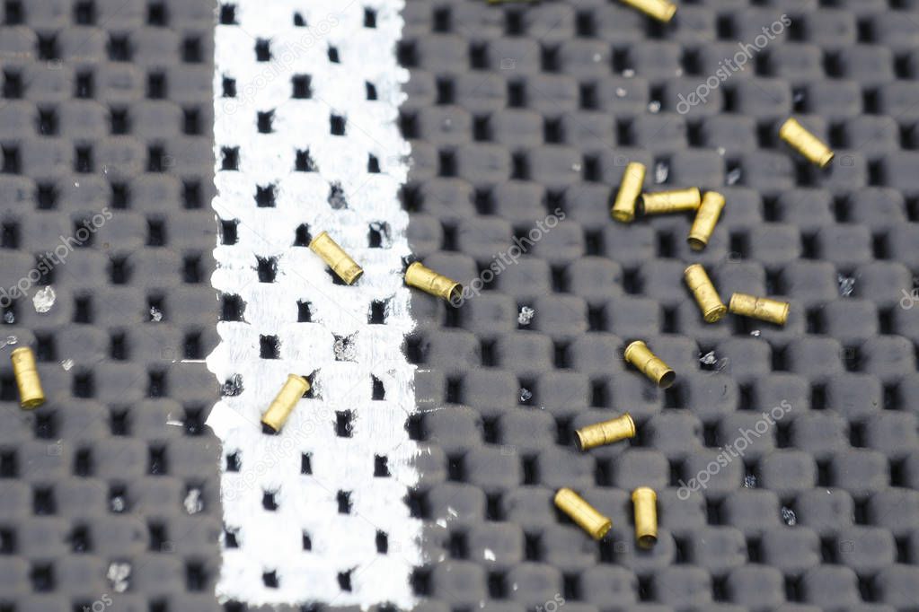 Sleeves from small-caliber cartridges on a black-and-white mat for firing