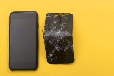 Telefon, sarı arka planda kırık bir telefonun yanında duruyor. Telefon tamir kavramı