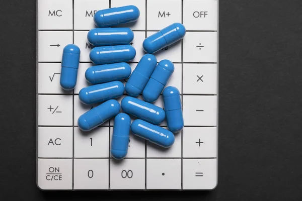 Blue pills are on the calculator. Pill sales concept. Close-up