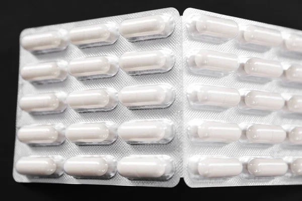 White pills in a pack on a dark background