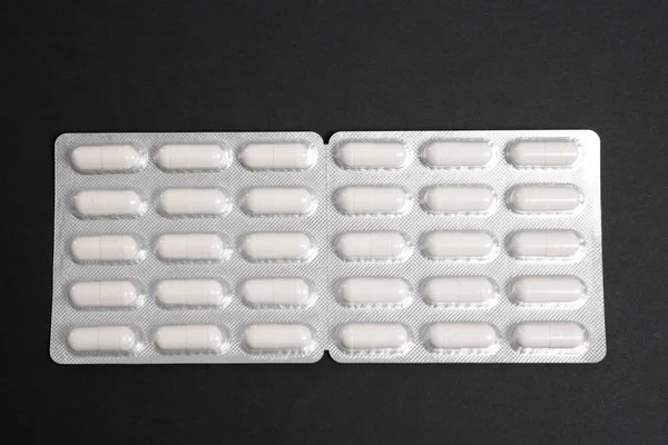 White pills in a pack on a dark background