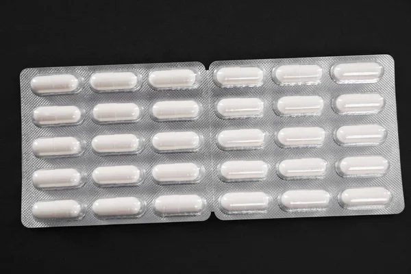 White pills in a pack on a dark background