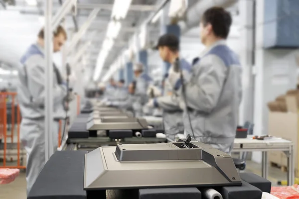 TV Assembly line at the factory. Background factory workers