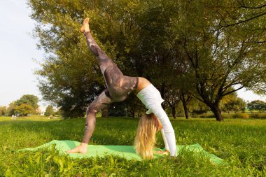 Parkta yoga yapan bir kız ellerinin üzerinde duruyor.