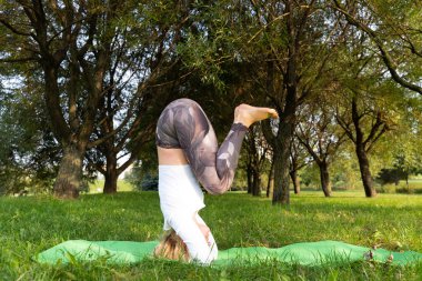 Kız parkta yoga yaparken kafasının üstünde duruyor.