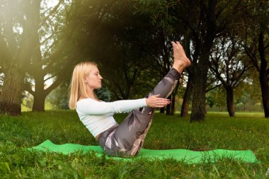 Sportif sarışın parkta yoga yapıyor. Ayarlanmış