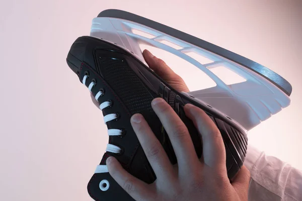 Male hand checks the sharpness of the blades of skates