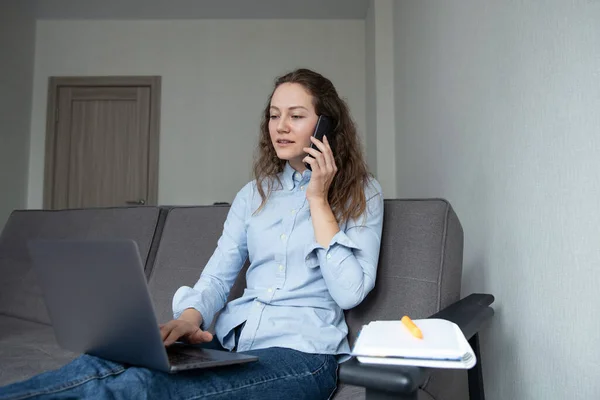 The girl talks on the phone and works online from home. Remote work