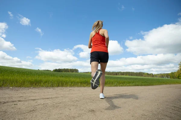 緑の野原や森を背景に砂の道を走っている少女 国内の夏のトレーニング — ストック写真
