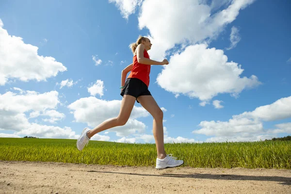 赤いTシャツを着た女の子が緑の畑を走っている 野外訓練 — ストック写真