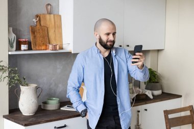 Mavi gömlekli ve siyah kotlu bir adam evdeki video bağlantısıyla telefonda. Serbest çalışma kavramı.