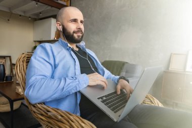 Acımasız bir adam sandalyede oturuyor ve dizüstü bilgisayar üzerinde çalışıyor. Evden çalışma kavramı.