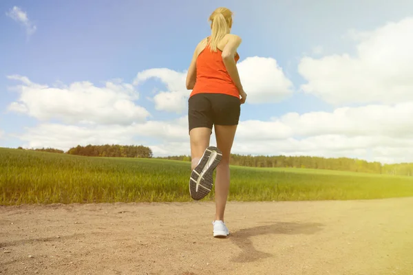緑の野原や森を背景に砂の道を走っている少女 国内の夏のトレーニング — ストック写真