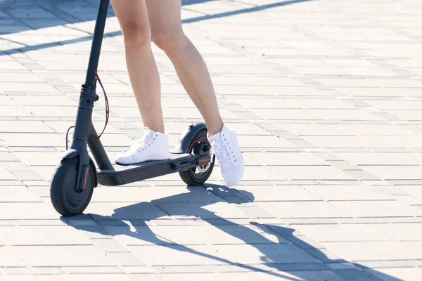 Elektrikli scooterla bir kızın bacaklarının yakın çekimi.