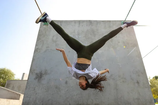 Uma Menina Pula Cabeça Para Baixo Contra Uma Parede Concreto — Fotografia de Stock