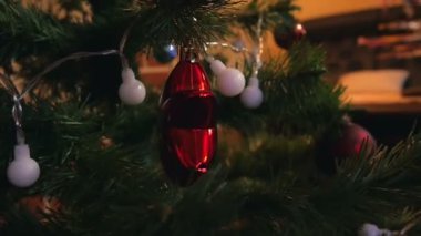 Ağır çekimde renk ışıkları ile yeşil Noel ağacı asılı kırmızı parlak yıldız.