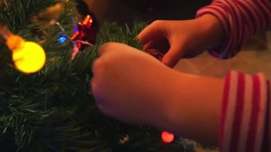 Küçük kız ile renk ışık ve parlak Ampüller Noel ağacı süsleme. Aile zaman filme ağır çekimde hd.