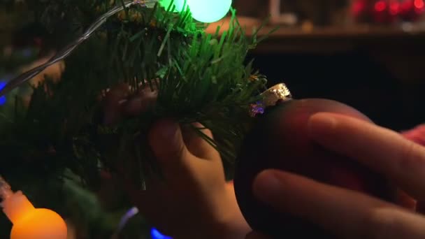 夜の時間でクリスマス ツリーに飾りを入れて女の子の小さな手 家族の時間お祭り準備を再び開始 — ストック動画
