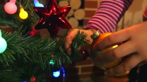 夜の時間でクリスマス ツリーに飾りを入れて女の子の小さな手 家族の時間お祭り準備を再び開始 — ストック動画