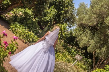 Tropic çiçek bahçesinde duran güzel beyaz gelinlik içinde gelin. Avustralya inanılmaz kum plaj düğün ateş.