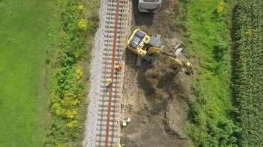 Hava: demiryolu imar sitesinde çalışma Ekskavatör üzerinde uçan. Güneşli güzel nehir yanında demiryolu de raylar yenileme filme.
