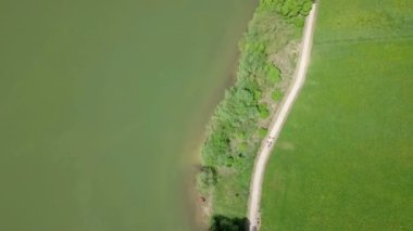 Hava: göl kıyısında yolu hiking iniyor. Göl yürüyen insanlar. Uçağı ile uçan ve güzel güneşli yaz gününde filme.