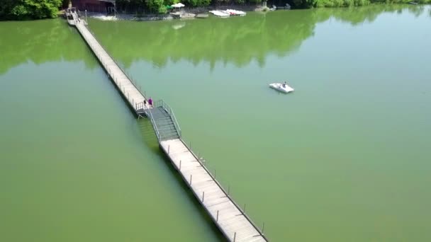 Aéreo Pessoas Irreconhecíveis Andando Sobre Ponte Flutuante Lago Verde Voando — Vídeo de Stock