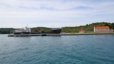 Yerleşik yük gemisi ve yanında küçük kilise ile beton İskelesi yanında yelken. Ağır çekimde Adriyatik Denizi'nde ipucu yelken üzerinde filme hd.