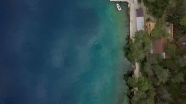 Hava: Adriyatik Denizi sahilinde yeşil ağaçlar ile tarafından taşlı sahil boyunca uçan. Yanında park edilmiş Yelkenli tekne ile küçük iskele üzerinde gidiş. Hırvatistan güzel mavi Adriyatik Denizi üzerinde yelken gezisi olarak film.